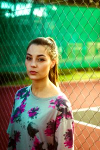 woman wearing floral top beside chain link fence during day photo