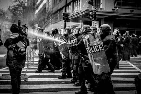 grayscale photo of police riot team on pedestrian lane photo