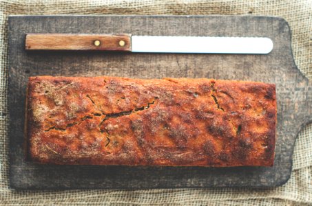 bread and bread knife on top of brown wooden chopping board