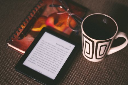 black E-book reader beside white and black mug photo