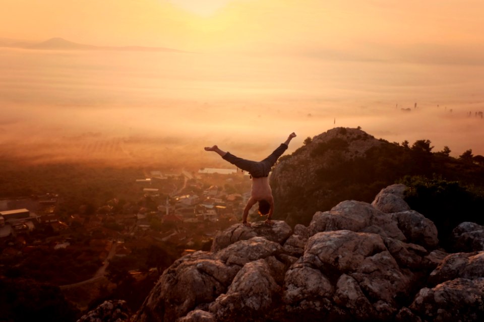 man doing handstand on boulders