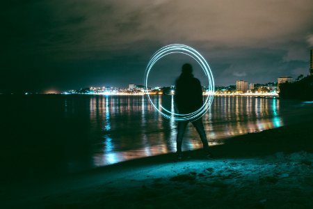 time-lapse photography of man playing with steel wool near seashore photo