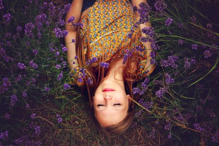 woman in yellow and teal top sleeping beside lavenders photo