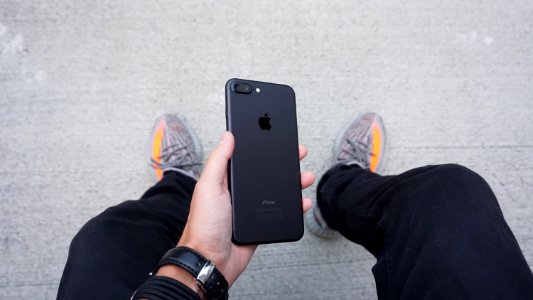 A person holding a black iPhone between their legs. photo