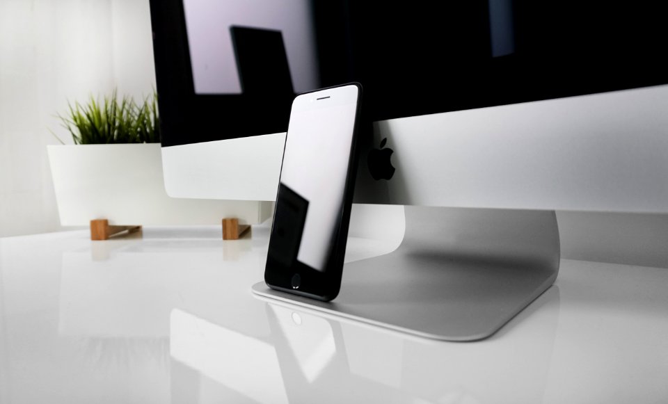 black iPhone 7 leaning on silver iMac