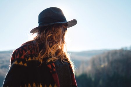 photo of person with blonde hair wearing hat staring at horizon photo