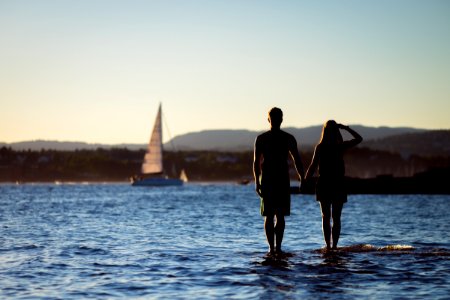 silhouette of man and woman on body of water at daytime