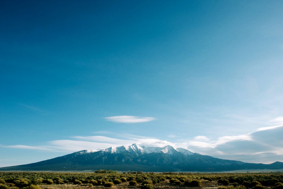 mountain near grass field under cloudy sky