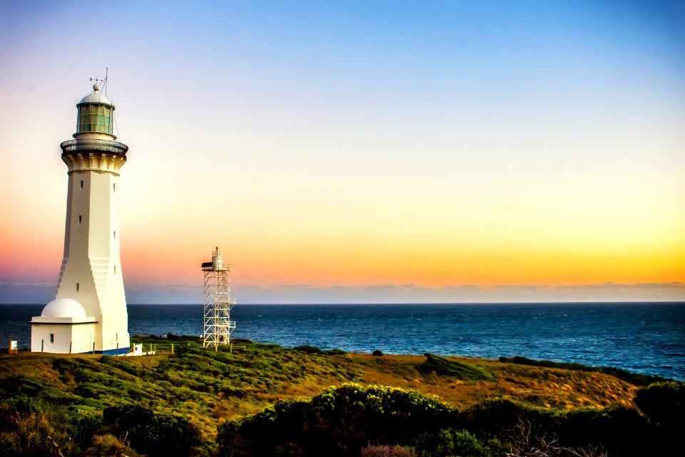 white concrete lighthouse near seashore at daytime