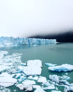 iceberg on body of water under cloudy sky