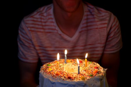 person holding white icing-covered cake