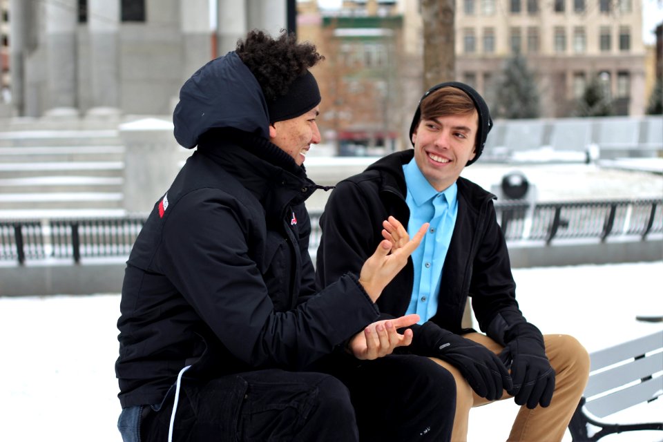 two men talking while sitting on bench
