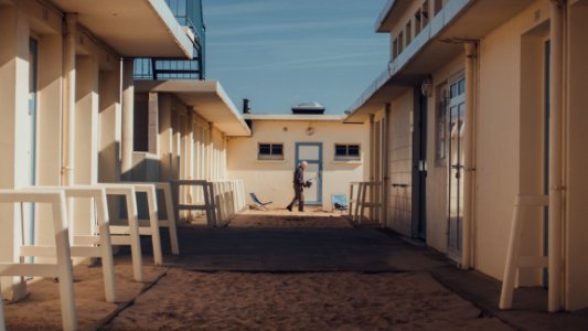 man walking between white buildings during daytime photo