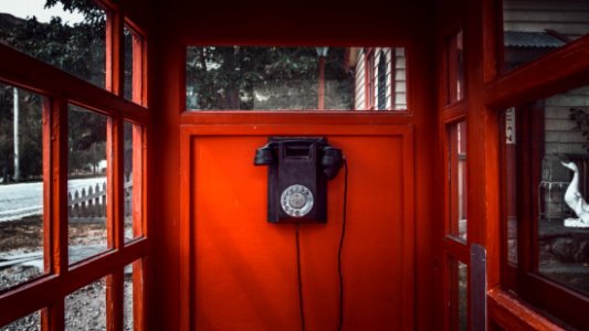 black rotary telephone mounted on red wooden wall photo