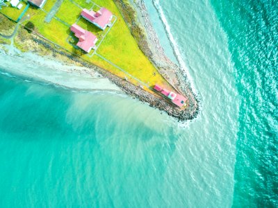 aerial photography of pink house at the edge of land near body of water photo