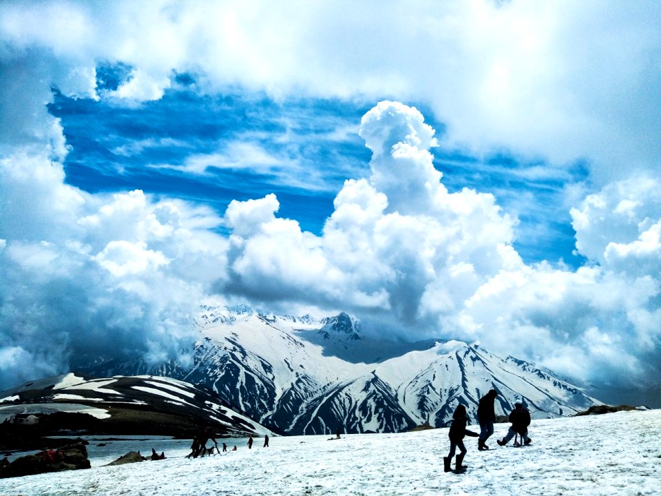 people standing on snow covered ground near mountains at daytime