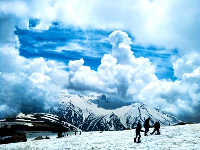 people standing on snow covered ground near mountains at daytime photo