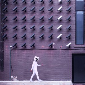 Marshmello walking down the side of the road with camera on the top of the building photo