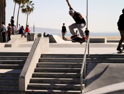 person riding skateboard performing stunt over stairs photo