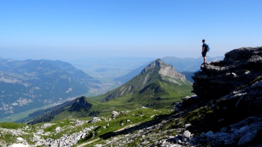 man standing near cliff facing mountains photo