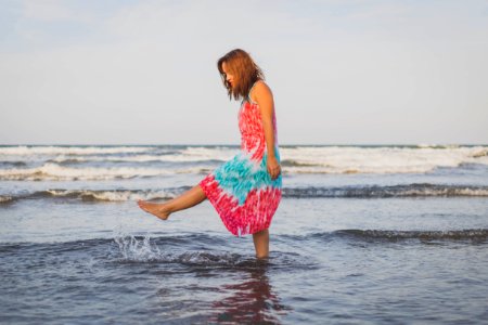 woman playing with water on shore during daytime photo