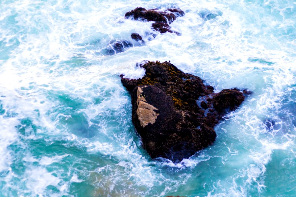 scenery of a rock on a body of water
