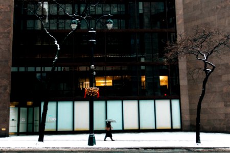 person walking beside building while holding umbrella