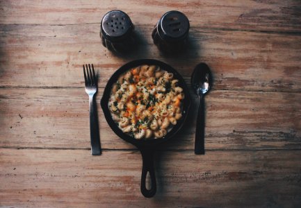 cooked food on black plate beside fork and spoon on brown wooden table photo