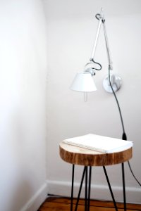 gray desk lamp mount on white wall under brown stool with white book on top near wall corner photo