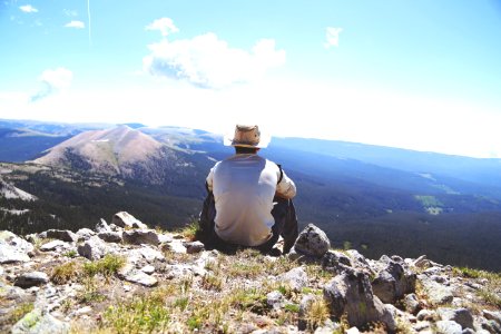 person sitting on a gray rock watching over a mountain photo