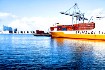 white and orange cargo ship with metal lifting equipment