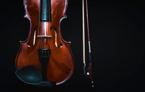 brown violin with bow in black background photo