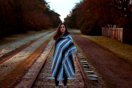 woman with blue and black striped scarf standing on brown train railway during daytime photo