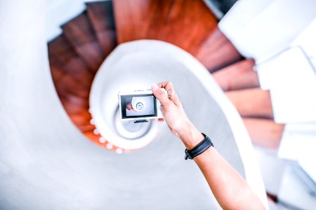 person taking picture of white spiral staircase