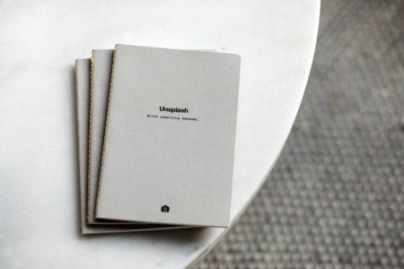 three white softbound books on white surface photo