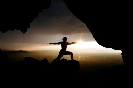 silhouette of person in yoga post on top of cliff during sunset photo
