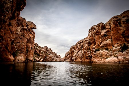 brown cliffs in front of body of water during cloudy sky photo