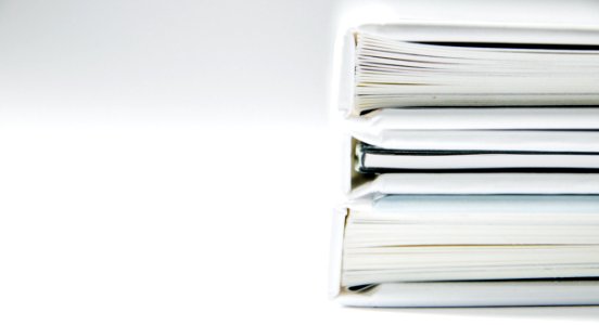 A stack of thick folders on a white surface