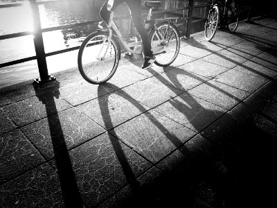 grayscale photo of a person wearing sneakers riding a bicycle photo