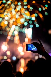 person holding smartphone capturing fireworks photo