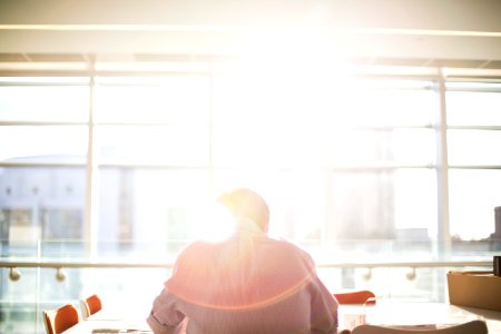 man sitting on chair in front on window during daytime