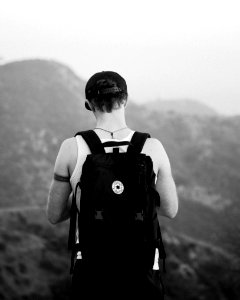 man standing facing mountains wearing backpack photo