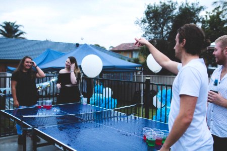 woman versus man playing beer pong under cloudy sky