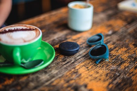 ceramic mug on saucer beside sunglasses photo