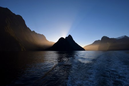 body of water near mountain under blue sky during day time photo