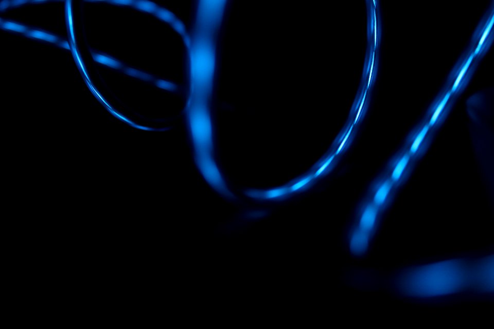 Blue light reflected in the surface of glossy swirling wires