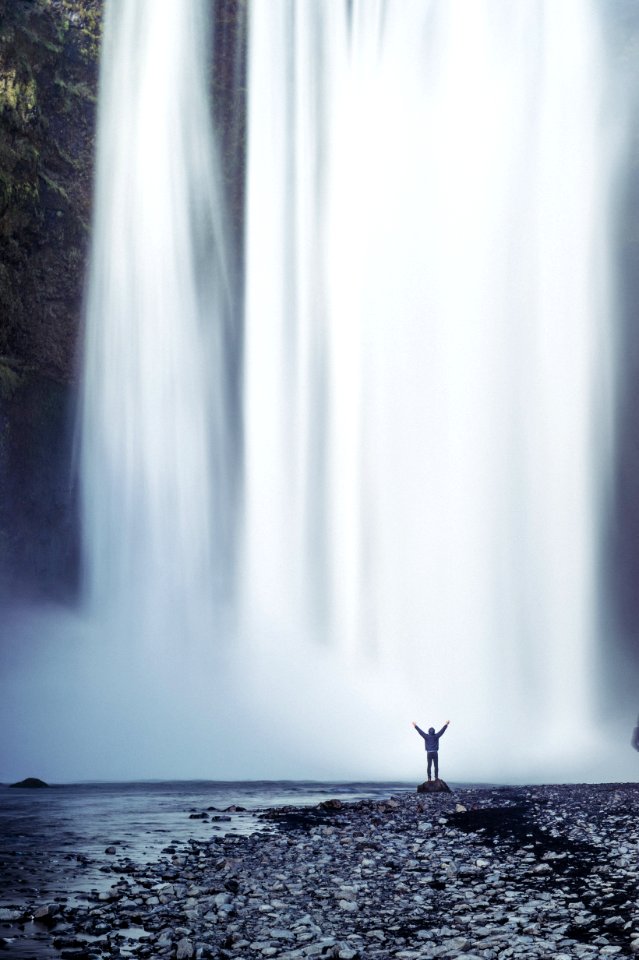 person standing beside waterfall