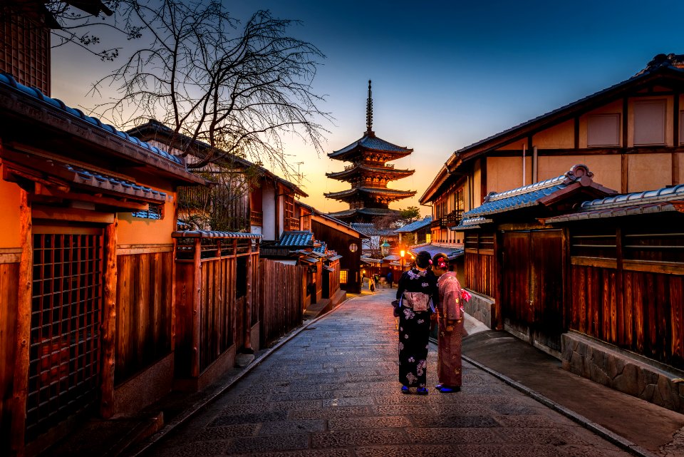 two women in purple and pink kimono standing on street