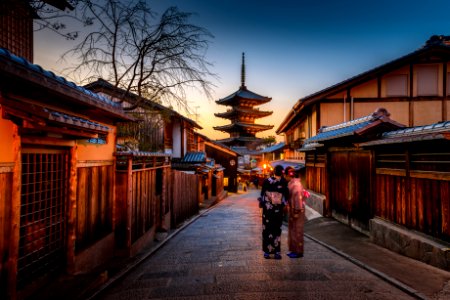 two women in purple and pink kimono standing on street