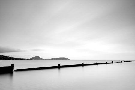 grayscale photo of body of water near mountain photo